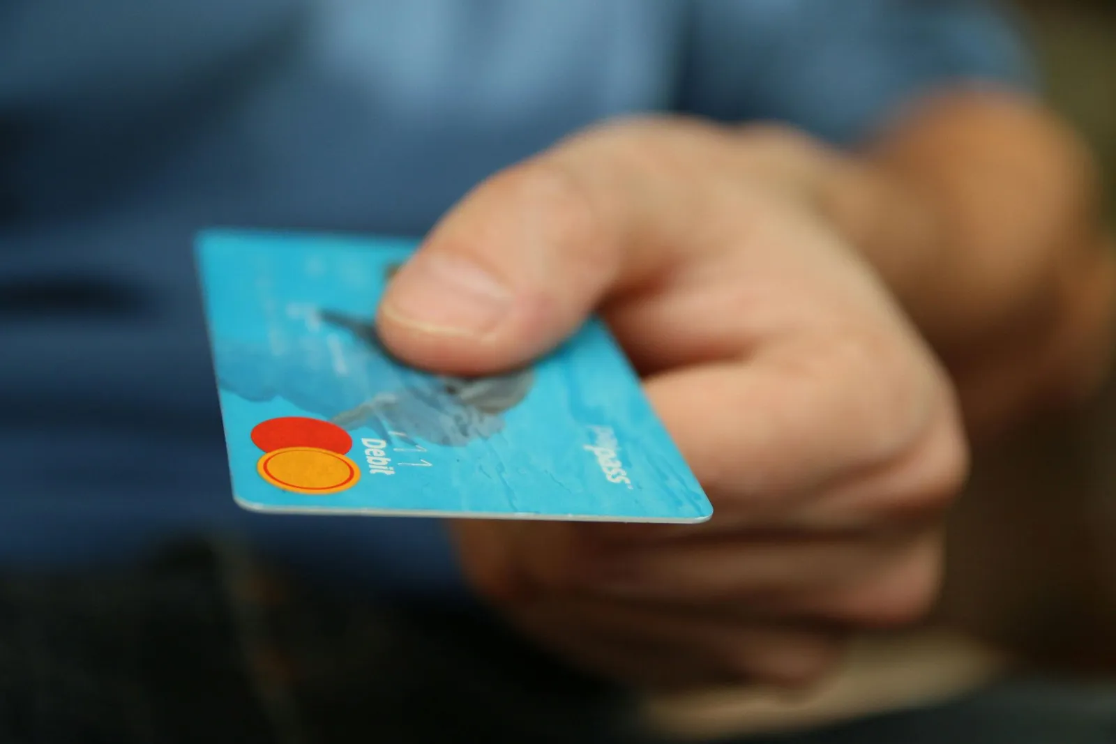Hand holding a blue Mastercard credit card, ready to pay.